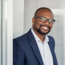 Portrait of happy african man wearing spectacles and looking at camera. Successful black buinessman with beard and glasses feeling confident at work. Portrait of mature business man in formalwear smiling.